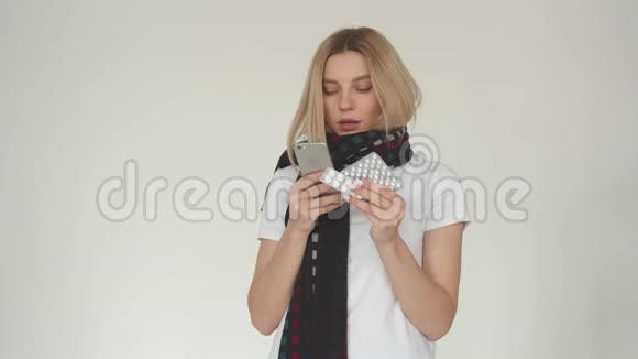 一个女孩在寻找流感药丸的说明的肖像一个白色背景的年轻女孩拿着一个水泡视频的预览图