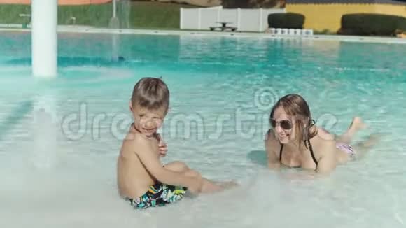 妈妈和她的小儿子在游泳池里玩视频的预览图