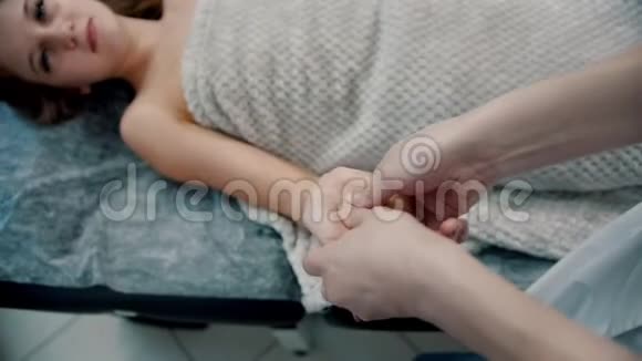 按摩按摩师在沙发上用手指揉搓年轻女子的手掌视频的预览图