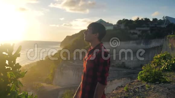 年轻的旅行者站在海边的岩石上欣赏美丽的日落视频的预览图