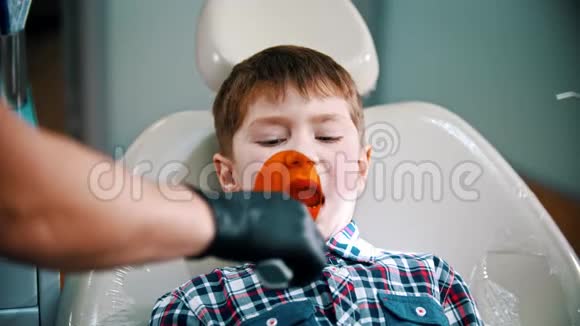 一个正在刷牙的小男孩把光聚合物灯放进嘴里视频的预览图