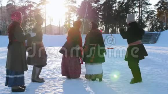 穿着俄罗斯民族服装的男女正在冬季公园里成双成对地跳舞视频的预览图