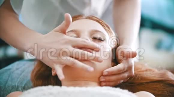 按摩按摩师用手掌揉捏一位年轻女子的下巴区域视频的预览图