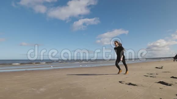 长发的年轻女子在海滩上练习前后双手弹簧和手推车可以看到海景慢动作视频的预览图