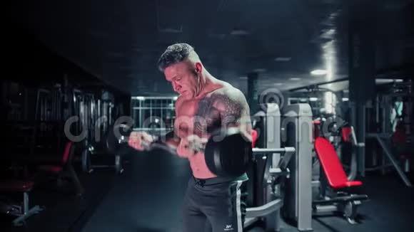 一个头发灰白的强壮男人在黑暗的健身房里拉着杠铃视频的预览图