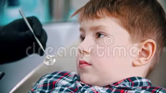 一个小男孩把他的牙齿做好了把光聚合物灯放进嘴里然后打开它视频的预览图