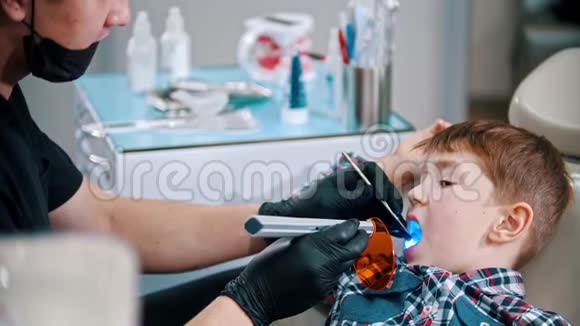 一个正在刷牙的小男孩把光聚合物灯放进嘴里把灯打开视频的预览图