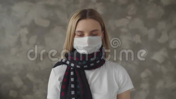 一个带着围巾戴着医用口罩的生病女孩看着体温计叹了口气一个年轻女子视频的预览图