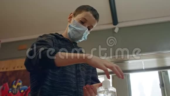 戴口罩的科罗纳大流行男孩使用洗手液预防冠状病毒视频的预览图