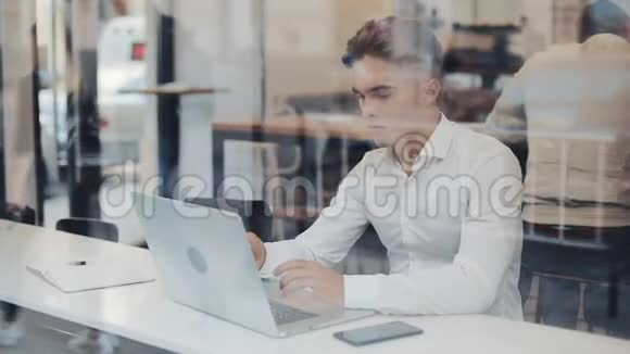 一位严肃的年轻商人坐在一家咖啡馆的桌子旁用笔记本电脑工作自由沟通信息技术成功视频的预览图