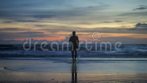 黄昏时分在海浪的背景下英俊的肌肉男在夕阳下奔跑的剪影视频的预览图