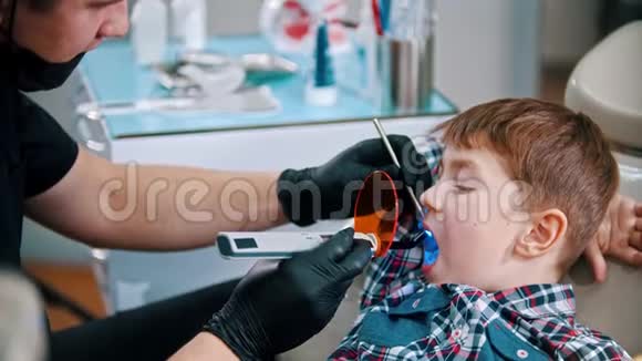 一个小男孩把他的牙齿做好了把光聚合物灯放进嘴里然后打开它视频的预览图