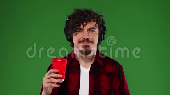 戴着听音乐的咖啡耳机的人英俊快乐的欧洲男人留着红色衬衫的胡子微笑着视频的预览图