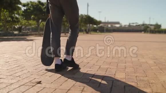 在公园的人行道上骑着滑板的男性滑板者的脚视频的预览图