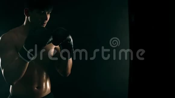 拳击概念一个戴手套的拳击手背着黑色的拳击袋个人体育娱乐慢视频的预览图