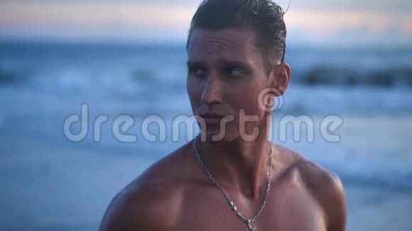 英俊的运动员训练有素的肌肉运动员的肖像在美丽的日落时在海滩上摆姿势视频的预览图