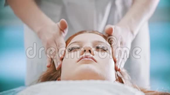 按摩按摩师用手掌揉捏一位年轻女子的颈部区域视频的预览图