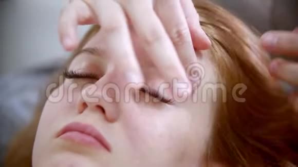 按摩按摩治疗师正在捏一个漂亮女人的脸视频的预览图
