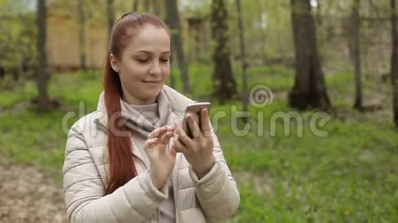 美丽的女性生活方式使用视频聊天享受与朋友的在线交流并在一个美丽的公园视频的预览图