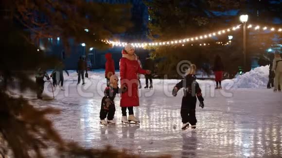 一家人年轻的母亲和两个孩子站在户外装饰好的溜冰场上视频的预览图
