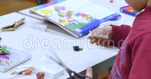 一个艺术工作室里的小男孩坐在一张桌子旁用剪刀剪一个图形学习过程或讲习班视频的预览图