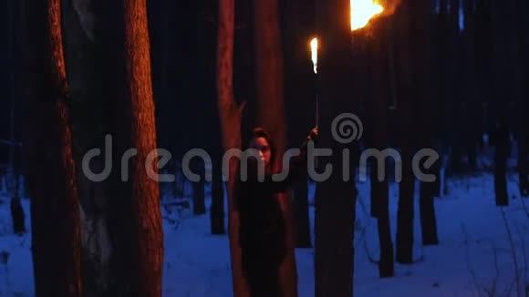 拿着火炬的年轻女子在黑暗的森林里行走视频的预览图