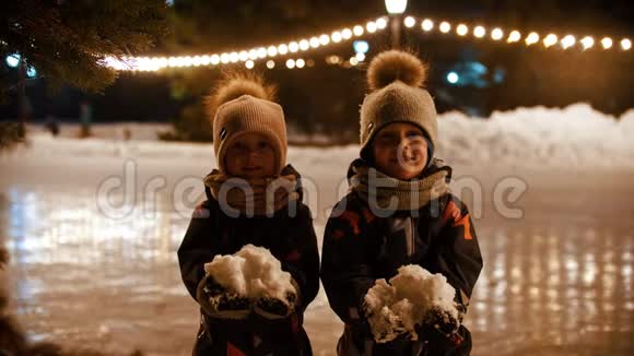 两个小孩站在公共冰场上向空中扔雪视频的预览图