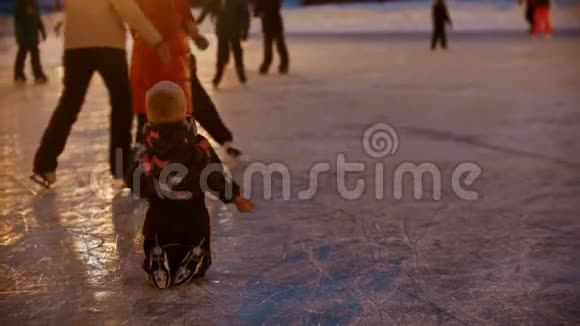 一个小女孩在冰上爬行她的母亲和哥哥在滑冰寻求她的帮助视频的预览图