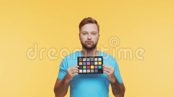 充满活力的背景下表现出来的年轻人画室肖像的英俊的人拿着彩色支票色彩和色彩视频的预览图