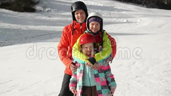 幸福的年轻家庭在滑雪服与有趣的孩子在明亮的冬天衣服手牵着手在公园里散步精彩绝伦视频的预览图