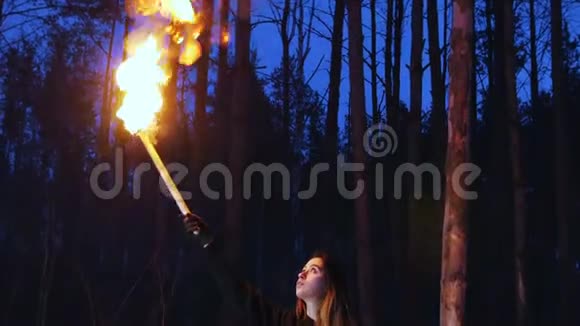 一位妇女在头顶上挥舞着火炬站在冬林中视频的预览图