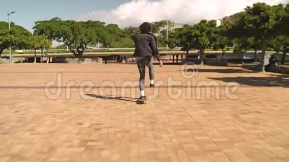 公园人行道上一个年轻人骑着滑板的后景视频的预览图