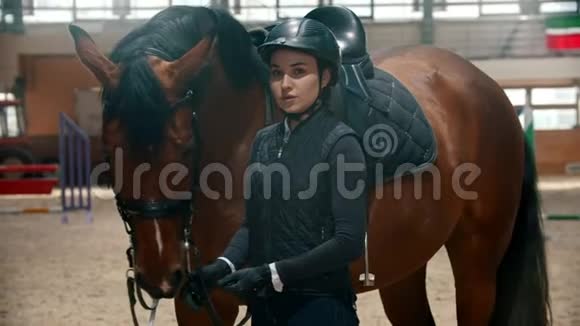 竞技场穿着特殊装备的年轻骑手和她的马站在一起微笑视频的预览图