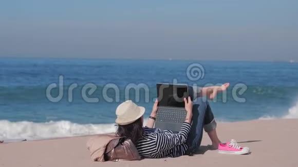 女人躺在沙滩上在外面工作度假时间视频的预览图
