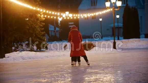 一个小孩试图在冰场上溜冰手牵着妈妈视频的预览图