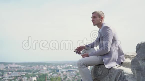 年轻的梦想商人与平板电脑的肖像他坐在一个驼峰上凝视着远处视频的预览图