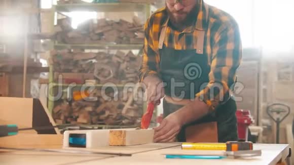 大胡子的人在车间里用圆锯切割木材用塑料棒推木板视频的预览图