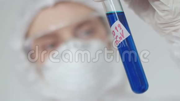 一位年轻的女科学家检查一支蓝色药物的试管一个戴防护面罩和眼镜的女孩在检查一项测试视频的预览图