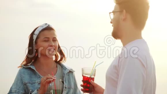 一个男人和一个女孩在一个鸡尾酒会上站在屋顶喝着夏天的城市鸡尾酒和交谈慢动作视频的预览图