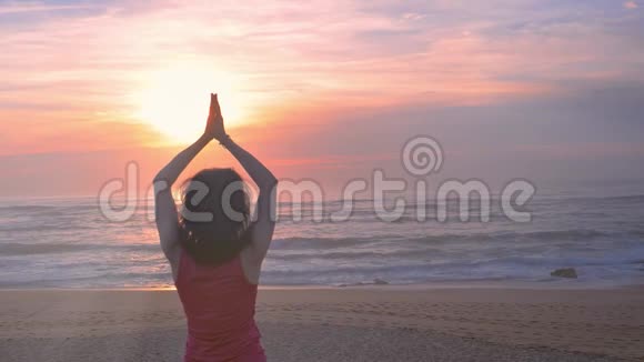 女人在沙滩上练习瑜伽美丽的夏日日落视频的预览图