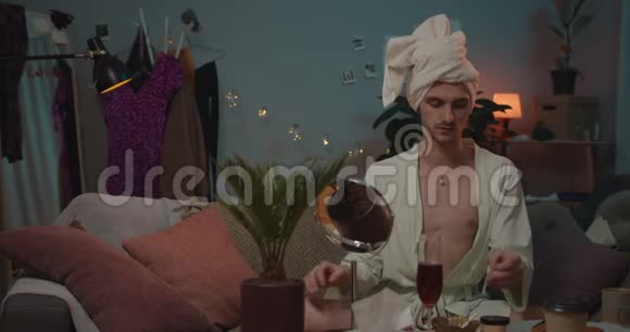 变性人头上戴毛巾看着小镜子准备参加聚会年轻人的正面视角视频的预览图