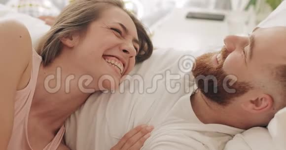 清晨幸福的夫妻躺在床上谈笑风生美丽的女人和她英俊的视频的预览图