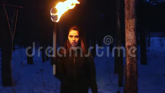 一个在冬天森林里拿着火把走到摄像机前的漂亮女人视频的预览图