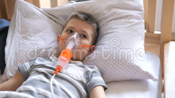 小男孩被用喷雾器治疗咳嗽小男孩使用雾化器进行治疗性吸入视频的预览图
