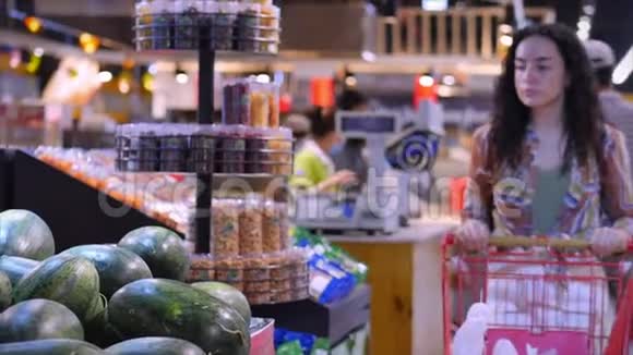 漂亮的年轻女人或母亲在超市购物选择食物西瓜鳄梨水果胡萝卜视频的预览图