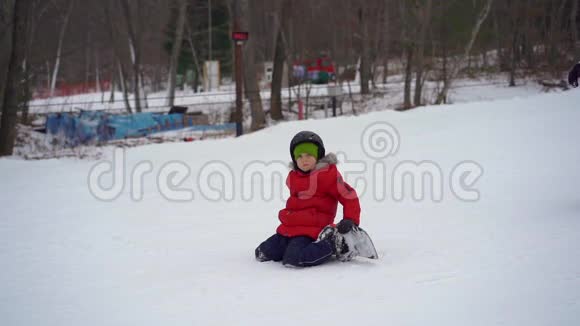 年轻人滑雪板教练教小男孩如何骑滑雪板冬季活动概念慢镜头视频的预览图