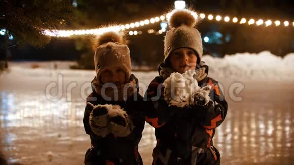 两个小孩站在冰场上向空中扔雪视频的预览图