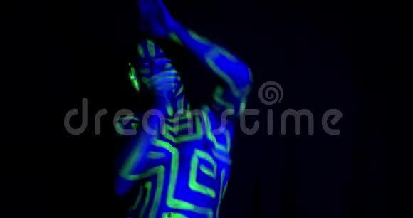 一个肌肉发达的男人的肖像有五颜六色的身体艺术在紫外线下跳舞4K视频的预览图