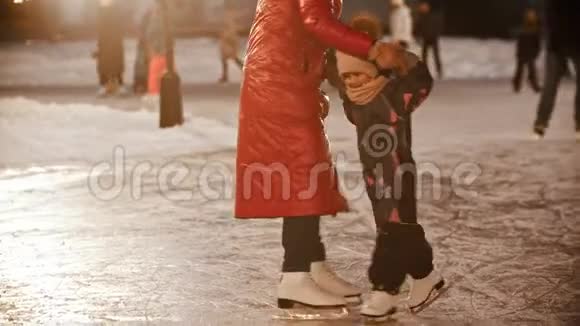 一个年轻的女人和她的孩子在溜冰场上滑冰在户外玩耍视频的预览图