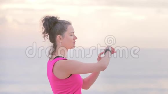 女子慢跑运动服装在海滨做运动看健身手表数据视频的预览图